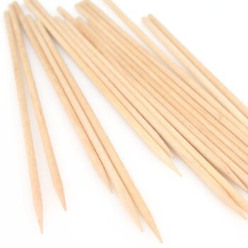 Wooden skewers with pointed ends scattered on white background