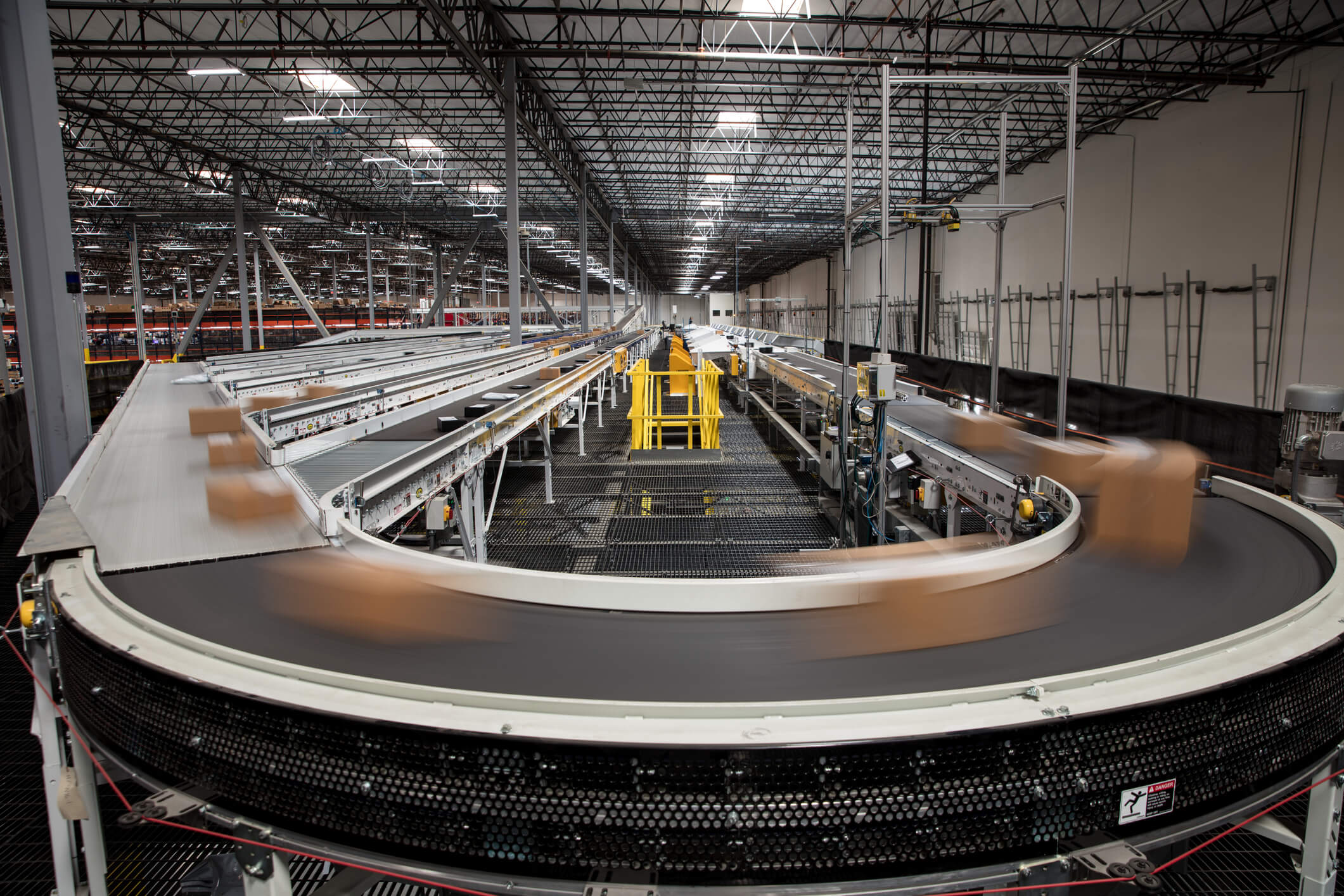 Packages blur as they rush past on the complex conveyor belt system that sorts them for delivery at a large fulfillment center.