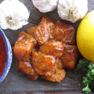 Raw chicken pieces glazed with Leonards Gluten Free Tikka Masala, presented with ingredients including garlic, lemon, and paprika, a product from Parkers Food Machinery Plus.