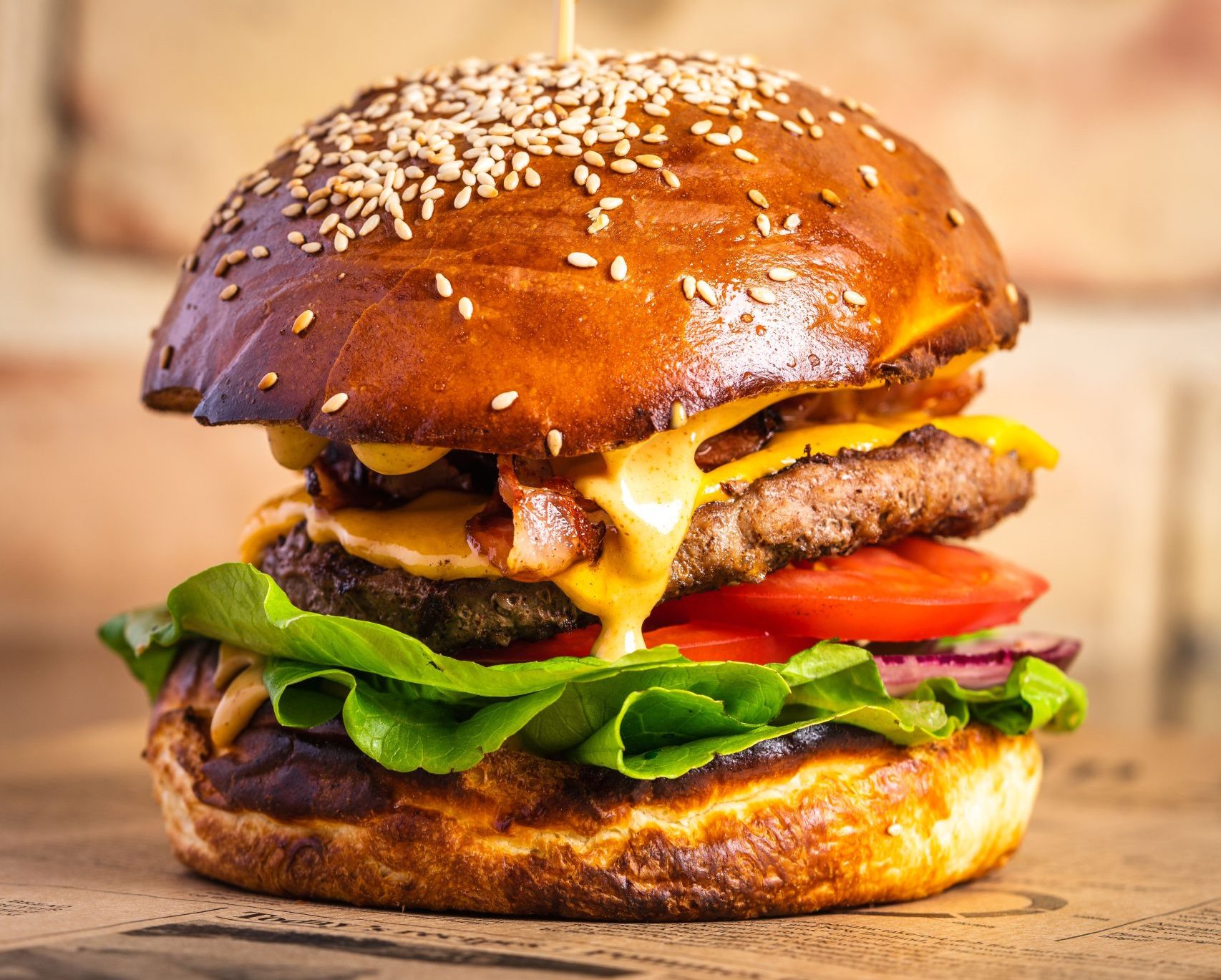 Close-up of gourmet hamburger with beef patty, melted cheese, bacon, lettuce, tomato, and red onion, highlighting burger seasoning ingredients and flavor profile