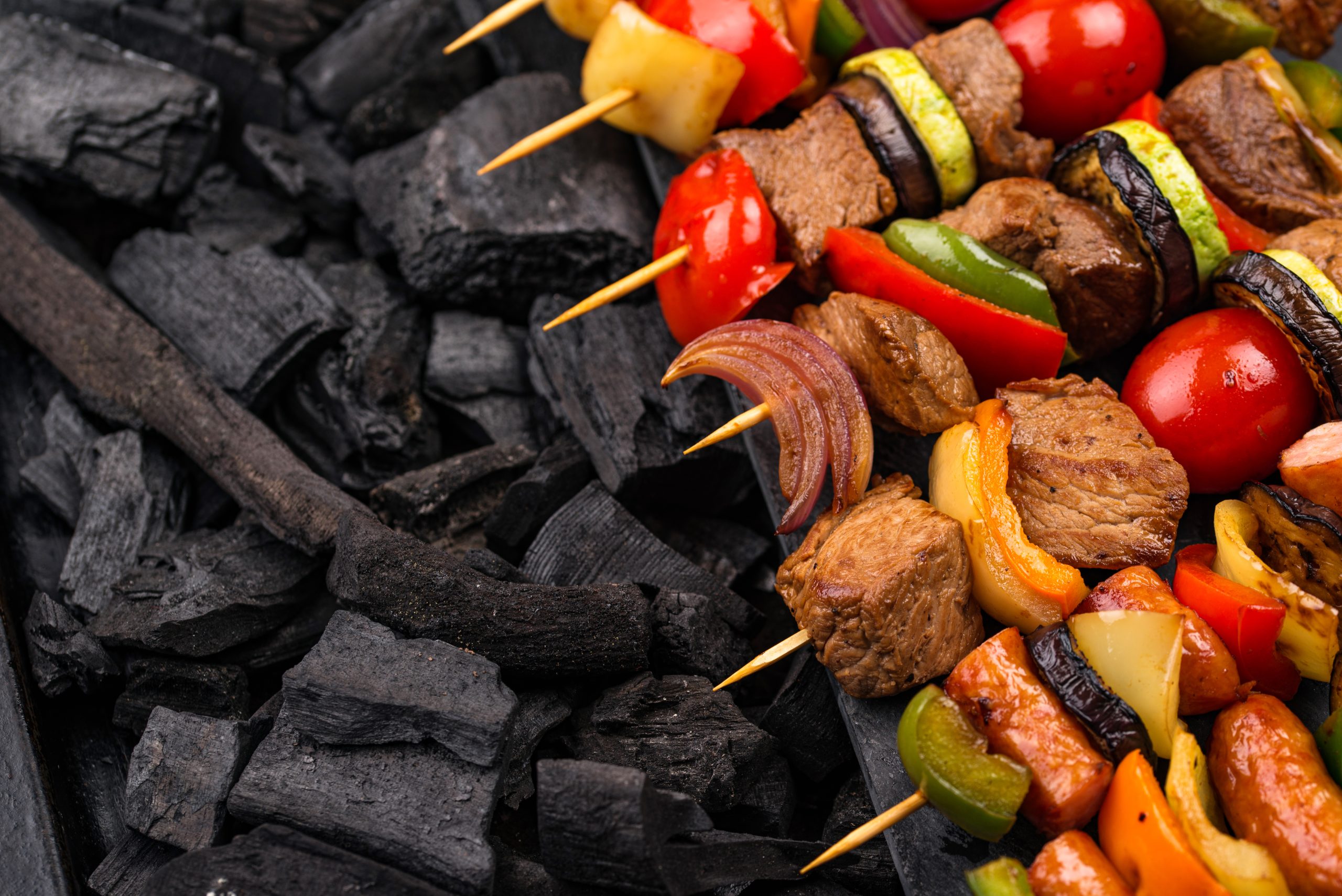 Grilled meat and vegetable skewers over glowing charcoal – vibrant BBQ scene showcasing smoky flavour and balanced grilling with Four Seasons BBQ Charcoal, featured in Parkers Food Machinery Plus blog “From Flames to Flavour”