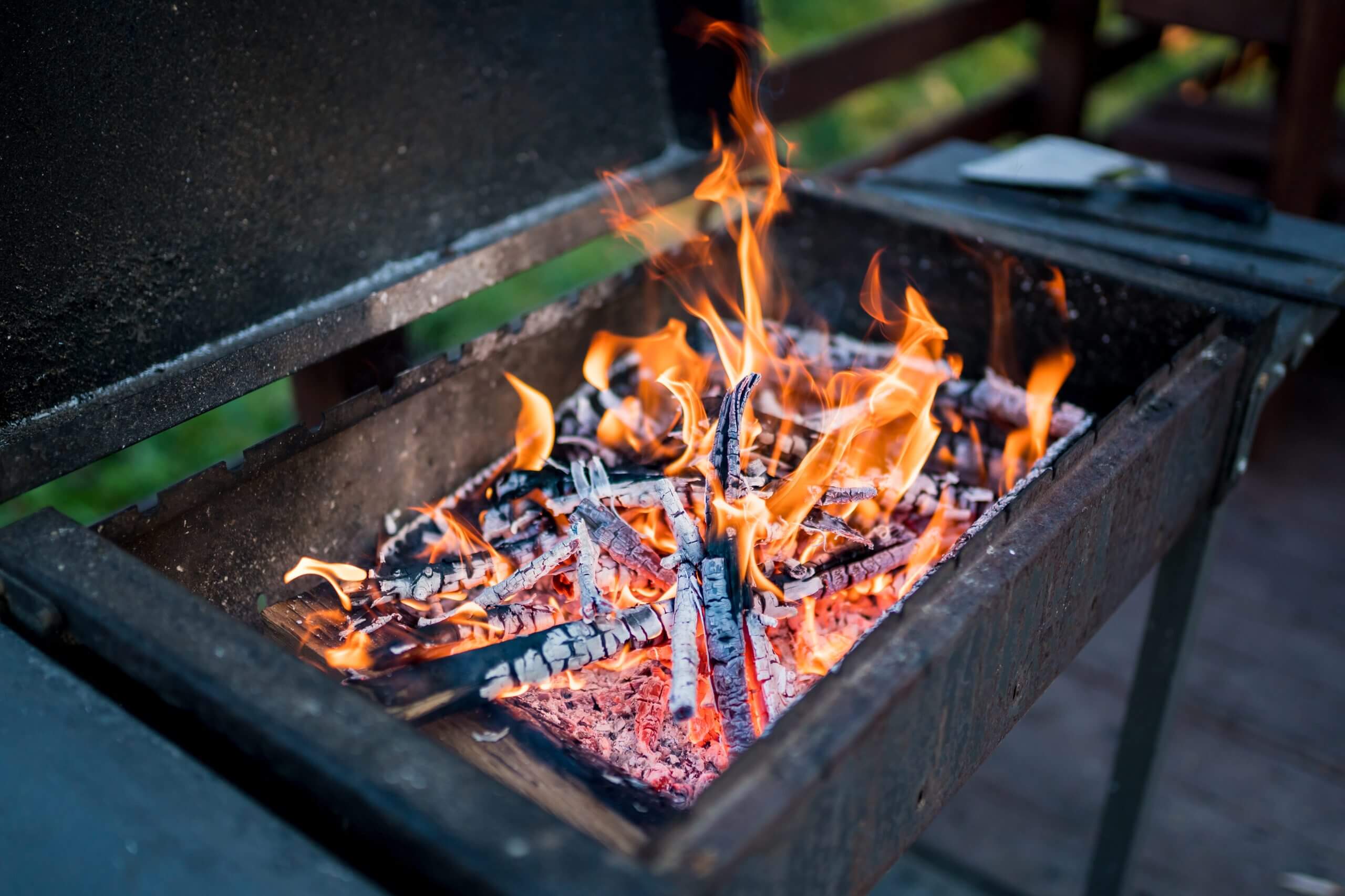 Outdoor BBQ grill with active wood fire and rising flames – visual guide for lighting a barbecue using natural fuel, featured in Parkers Food Machinery Plus blog “How to Light a BBQ”