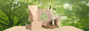 Eco-friendly packaging products made from recyclable paper and cardboard displayed on a wooden table against a green forest background.