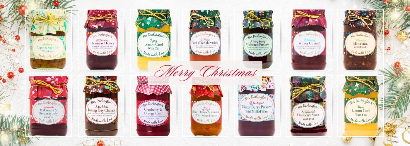 A festive banner featuring a full range of Mrs Darlington’s Christmas preserves, chutneys, curds, marmalades, and sauces. Each jar is decorated with colourful seasonal fabric covers and gold ties, arranged in a single row with a ‘Merry Christmas’ message in elegant red script across the centre. Background includes subtle Christmas greenery, baubles, and glitter for a holiday theme at PFM Plus.