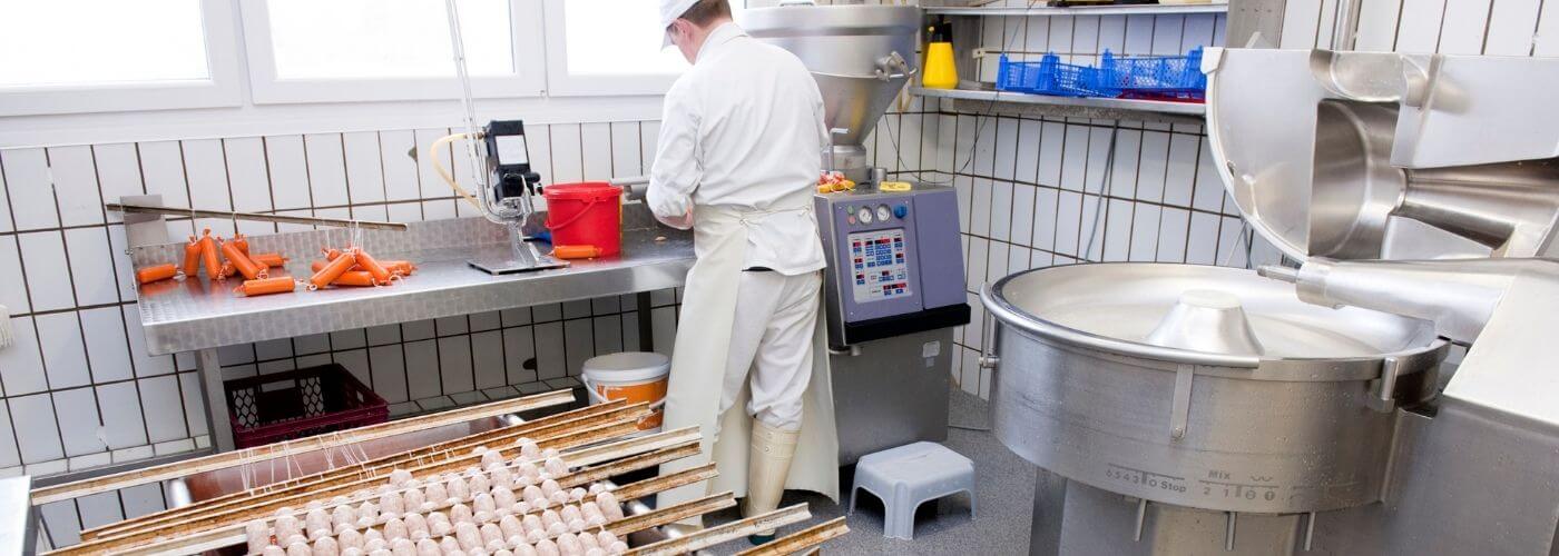 Butcher working in a production room with pre-owned food processing machinery for sausage making from Parkers Food Machinery Plus.