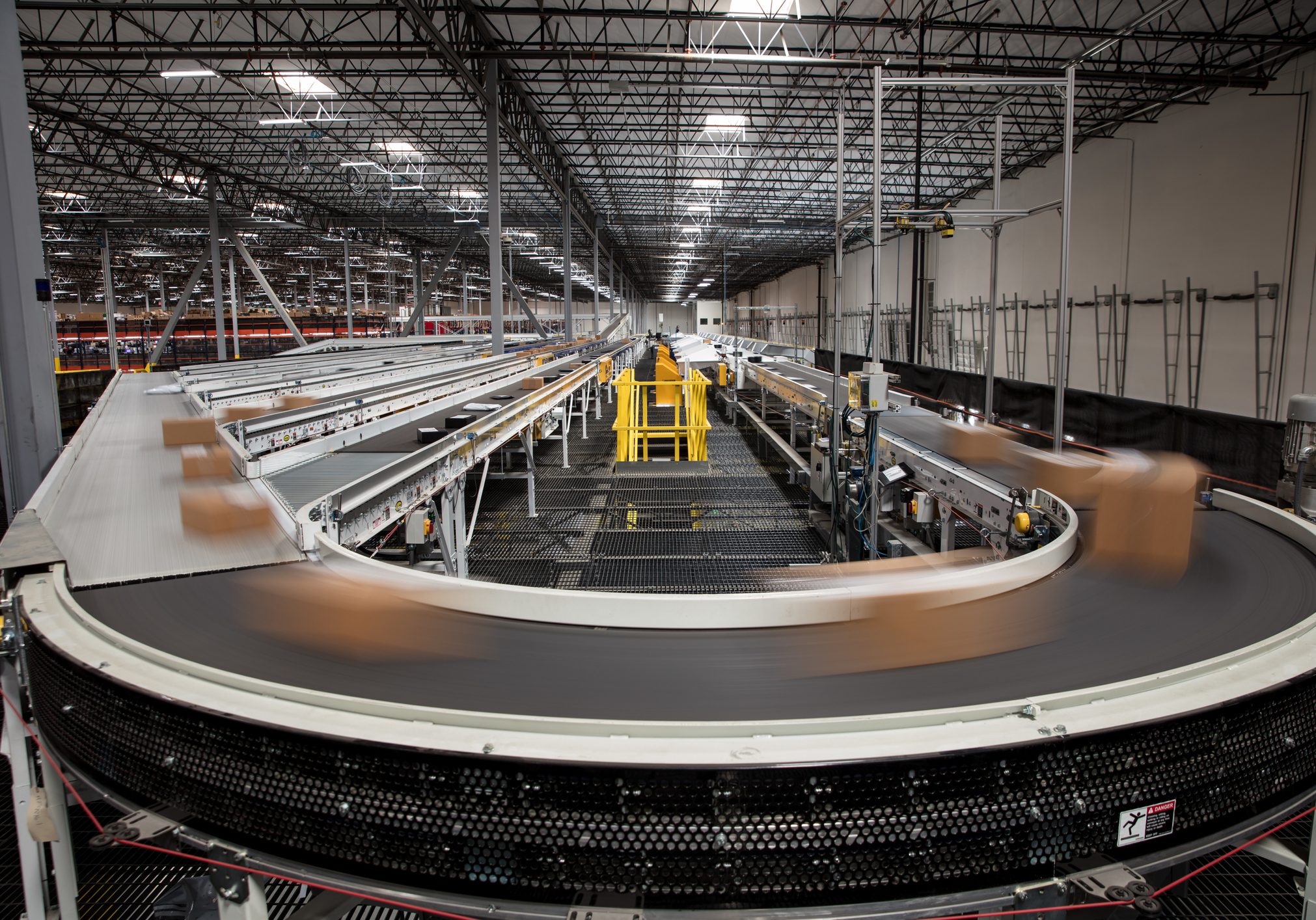 Packages blur as they rush past on the complex conveyor belt system that sorts them for delivery at a large fulfillment center.